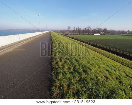 Panorama Of Walkway On Barrage At Countryside Landscapes Of Green Grassy Field, Forest On Artificial