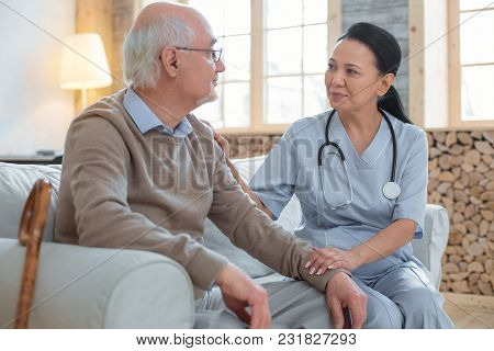 Your Health Today. Asian Adorable Doctor Wearing Uniform While Staring At Senior Man Who Sitting Nex