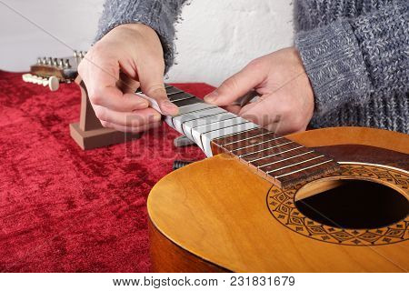 Musical Instrument Guitar Repair And Service - Worker Preparation Pasting Of Frets For Grinding.