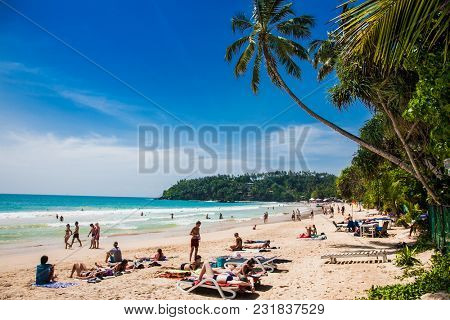 Mirissa Beach, Sri Lanka - JAN 2, 2017:  Tourists walking on the sand while enjoying the view across the wonderful beach of Mirissa on Jan 2, 2017. Sri Lanka.