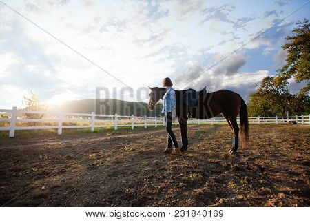 A Young Woman Riding A Horse Looks At The Sunset