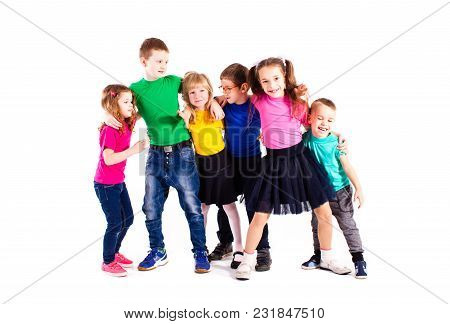The Happy Kids Are Standing Together Embracing Each Other In Colorful Clothes Isolated On White Back