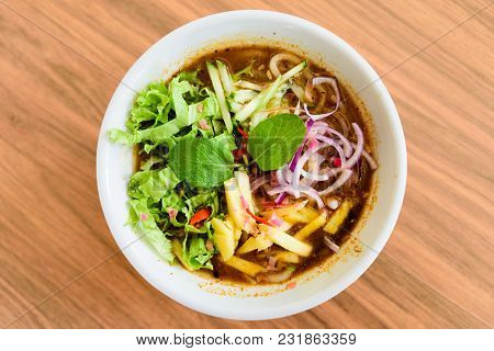 Laksa On Wooden Table. Laksa Is A Spicy Noodle Soup Popular In The Peranakan Cuisine.
