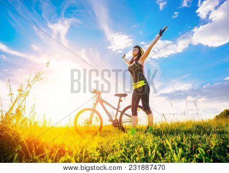 Free Happy Woman Enjoying Freedom On Bike On Nature At Sunset. Sporty Girl Raised Her Hands Up And E