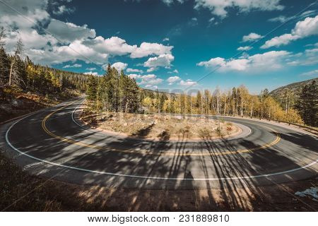 Highway with hairpin turn (switchback) at autumn sunny day in Rocky Mountain National Park. Colorado, USA. 