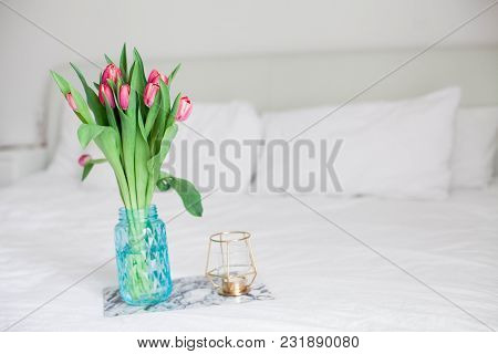 Home Interior. Bedroom. A Bouquet Of Tulips In A Glass Vase, A Candle, A Tray, A Box With A Gift Sta