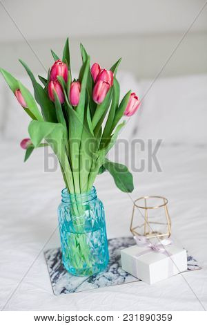 Home Interior. Bedroom. A Bouquet Of Tulips In A Glass Vase, A Candle, A Tray, A Box With A Gift Sta