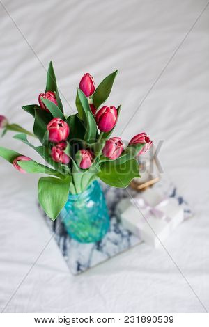 Home Interior. Bedroom. A Bouquet Of Tulips In A Glass Vase, A Candle, A Tray, A Box With A Gift Sta
