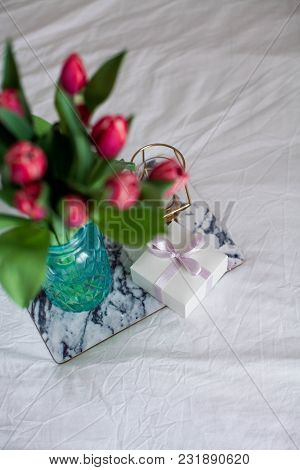 Home Interior. Bedroom. A Bouquet Of Tulips In A Glass Vase, A Candle, A Tray, A Box With A Gift Sta