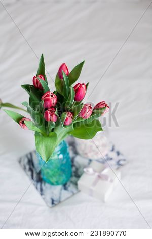 Home Interior. Bedroom. A Bouquet Of Tulips In A Glass Vase, A Candle, A Tray, A Box With A Gift Sta