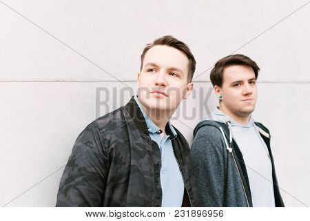 Two Male Teenage Friends Or Brothers Leaning Against Wall With Copy Space