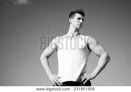 Man Bodybuilder Posing On Blue Sky. Athlete In Green Tshirt On Sunny Day. Healthy Lifestyle Concept.