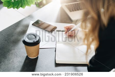 Close-up Of Notebook On Table And Pen In Female Hand. Girl Is Making A Note In A Notebook, Planning.