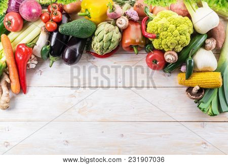 Different colorful vegetables arranged as a frame. Wooden background.
