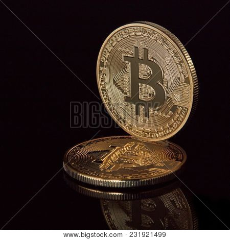 New virtual money stacked crypto currency golden bitcoins coins on black reflective surface background.