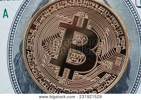 Close-up of gold Bitcoin on hundred dollars bills
