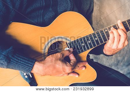 Hand Of Man Holding White Plectrum Playing Guitar