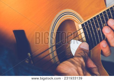 Hand Of Man Holding White Plectrum Playing Guitar