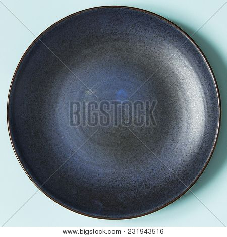 Empty Ceramic Round Plate On Background In Blue Pastel Colors.  Top View With Copy Space.