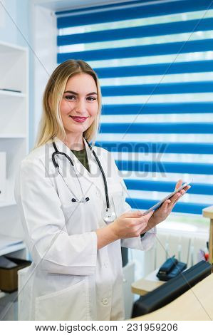 Smiling Female Doctor With Stethoscope At The Reception.