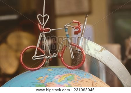 Miniature Bicycle Figure On Geography Globe Or Planet Sphere Model, Cyling To Destination.