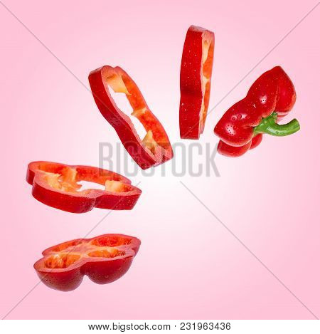 Creative Concept With Flying Red Paprika. Sliced Floating Pepper. Levity Capsicum Vegetable On Pink 