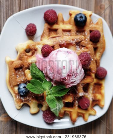 Plate of belgian waffles with ice cream and fresh berries - raspberries and blueberries.top view close-up.