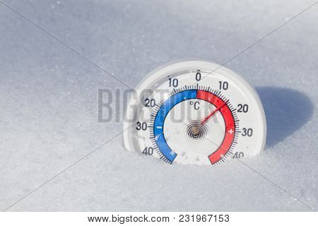 Thermometer with celsius scale in melting snow showing plus 15 degree temperature hot spring weather or global warming concept