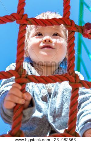 Multracial Toddler Boy Climbing On A Playground Ropes