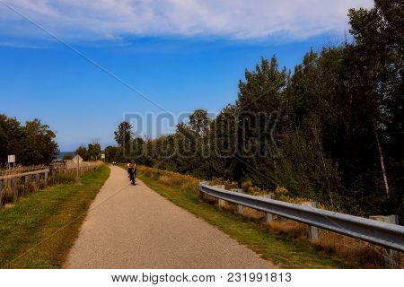 Charlevoix Michigan on Lake Michigan is a beautiful vacation destination.  A bike and running trail connects this city to popular Petoskey. A biker is on the path.