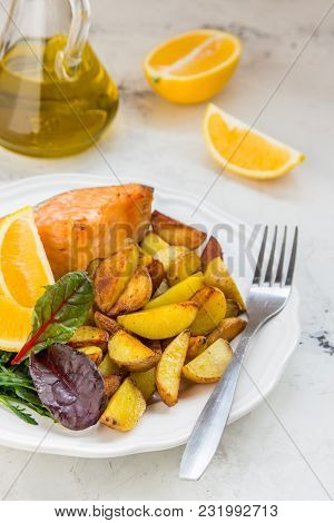 Fried Potatoes With Fish And Green Salad On A White Plate