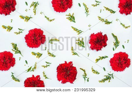 Floral Pattern Made Of Red Carnations, Green Leaves, Branches On White Background. Flat Lay, Top Vie