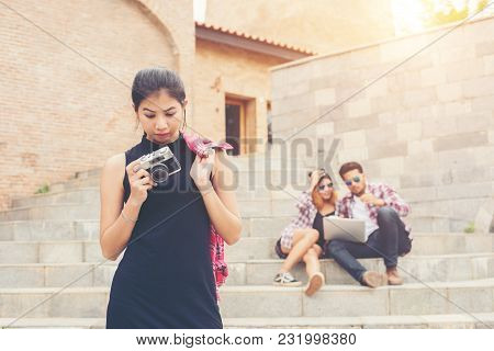 Young Pretty Hipster Teenager Standing And Smiling To Camera With Blurred Of Teenger Sitting On Stai