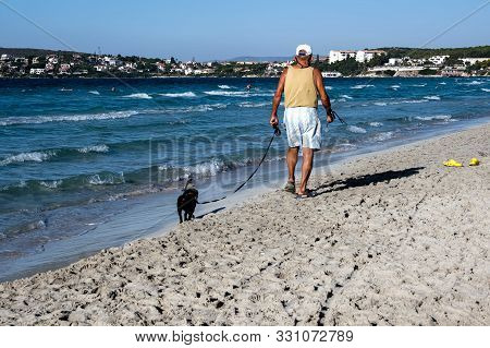 Senior Man Walking His Dog At The Beach. Cesme, Izmir, Turkey.