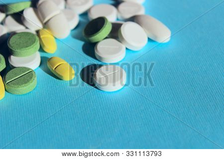 White, Yellow And Green Peels Scattered On Blue Background.  Medical Concept.