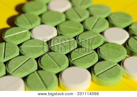 Green And White Pills Scattered On Yellow Background. Helth And Medical Concept. Colorful Drugs Back