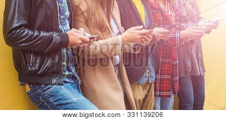 Titolo: Friends Standing By The Wall While Holding Smartphones- Young People Using Devices- Teenager