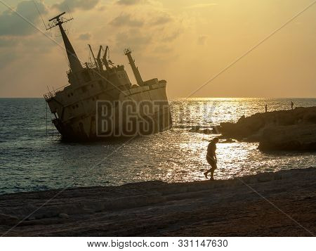 Silhouette Of A Girl On Sunset Near The Old Ship On The Mediterranean Sea Background. The Old Edro I