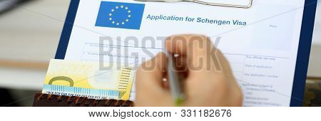Male Hand Hold Silver Pen With Passport. Filling Schengen Apllication Form Concept