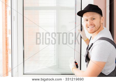 Worker In Uniform Installing Blinds On Plastic Upvc Window