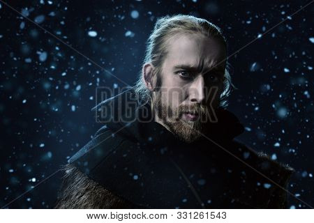 Portrait of a medieval pilgrim in old historical clothes over winter background. Historical reenactment. 