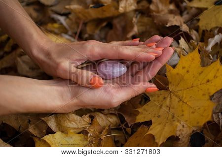 Female Hand With Orange Manicure Holding Pink Quartz Yoni Egg For Vumfit, Imbuilding Or Meditation O