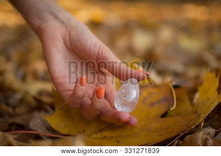 Female Hand With Orange Manicure Holding Transparent Violet Amethyst Yoni Egg For Vumfit, Imbuilding