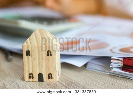 Closeup Of Home And Businesswoman Use Calculator For Analyzing Data Of Market Report For Loan Home.