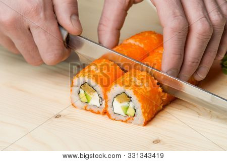 Male Hands Cut Prepared Rolls. Delicious Sushi With Cream Cheese, Avo, Caviar, Tuna Like In The Best