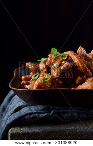 Pieces Of Meat Stewed In Tomato Sauce With Spices Served In A Clay Bowl Against Black Background
