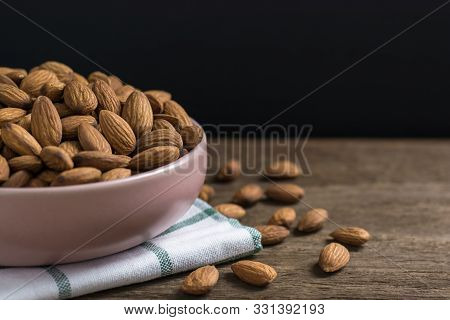 Almonds In Pink Porcelain Bowl On Wooden Table With Copy Space.black Background