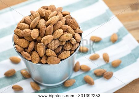 Almonds In Stainless Bucket On Wooden Table