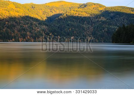 Placid Lake At Golden Hour With Mountains And Lake Water That Is Smooth
