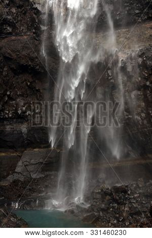 Hengifoss Canyon with the Hengifoss Waterfall, the third highest waterfall in Iceland is surrounded by basaltic strata with red layers of clay between the basaltic layers